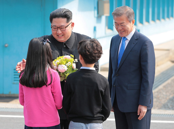 Nhà lãnh đạo Kim Jong-un tươi cười nhận hoa từ các em bé Hàn Quốc sau khi bước qua biên giới. Ảnh: Reuters.