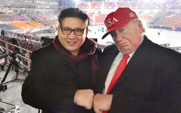Người đóng giả Tổng thống Trump đội chiếc mũ đỏ có chữ USA (Mỹ) chụp ảnh thân thiết với “ông Kim”. Ảnh: SCMP.