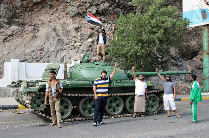 Các phần tử ly khai miền Nam Yemen giơ tay biểu tượng chiến thắng khi đứng cạnh chiếc xe tăng ở thành phố cảng Aden.