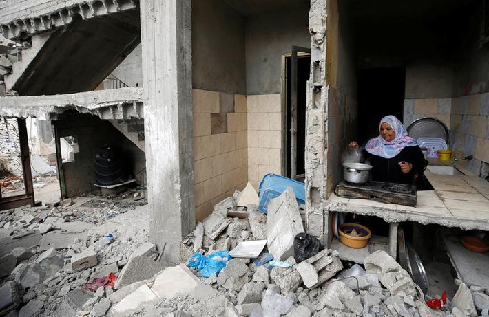 Người phụ nữ Palestine nấu ăn trong ngôi nhà bị hư hại ở Gaza.