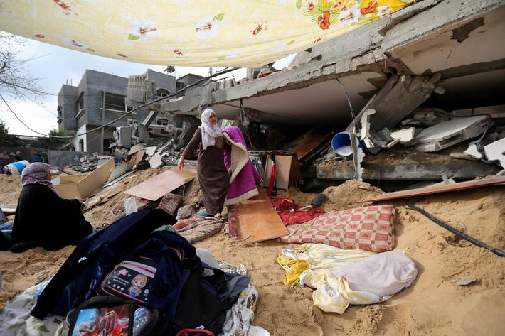 Một phụ nữ Palestine thu dọn đồ đạc sau khi trở về ngôi nhà bị phá hủy của cô ở Gaza ngày 21/5.