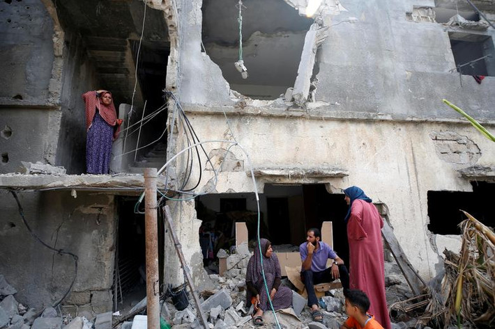 Một vài người dân Palestine ngồi giữa đống đổ nát của một ngôi nhà bị phá hủy ở Beit Hanoun, phía bắc Dải Gaza, ngày 21/5.