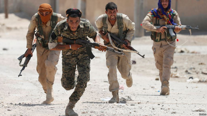 Theo VOA, lực lượng SDF đã tiến đến khu thành cổ ở Raqqa và giành lại quyền kiểm soát khoảng 1/4 diện tích thành phố. Ảnh: Các chiến binh người Kurd chạy qua một con phố ở Raqqa, Syria, ngày 3/7/2017. (Nguồn: Reuters)