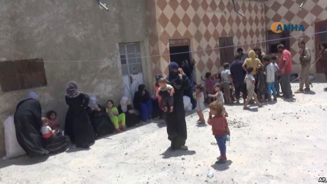 Các cư dân tập trung trước một ngôi nhà mới được lực lượng SDF giành lại ở Đông Raqqa ngày 6/7. Ảnh: AP.