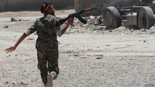 Một chiến binh người Kurd bắn các tay súng IS trong lúc chạy qua một con phố ở Raqqa ngày 3/7. Ảnh: Reuters.