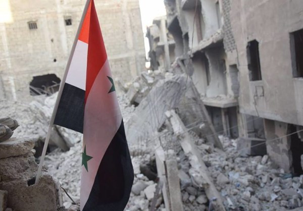 Quốc kỳ Syria xuất hiện giữa đống đổ nát ở Đông Damascus. Ảnh: FNA.