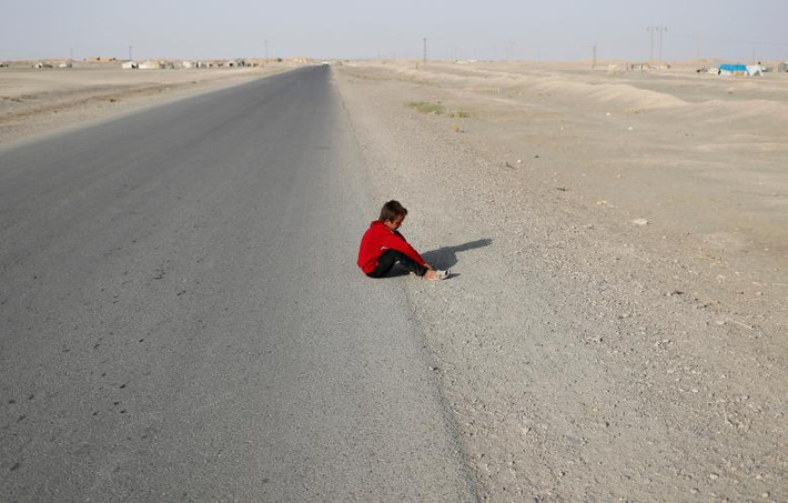 Một bé trai sơ tán khỏi thành phố Raqqa ngồi trên con đường gần làng Karama.