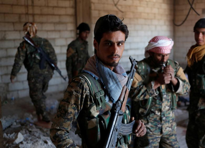 Một số thành viên YPG đứng trong ngôi nhà đổ nát ở Raqqa.