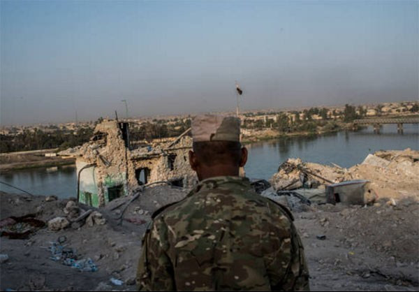Một binh sĩ đứng nhìn tòa nhà đổ nát ở Mosul. Ảnh: FNA.