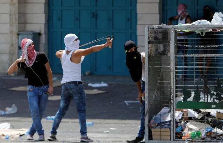 Một người biểu tình Palestine dùng súng cao su “bắn” đá về phía các binh sĩ Israel trong các cuộc đụng độ ở thành phố Bethlehem, Bờ Tây, ngày 21/7.