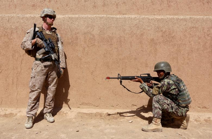 Lính Mỹ đứng cạnh quan sát một binh sĩ Afghanistan trong buổi tập luyện.