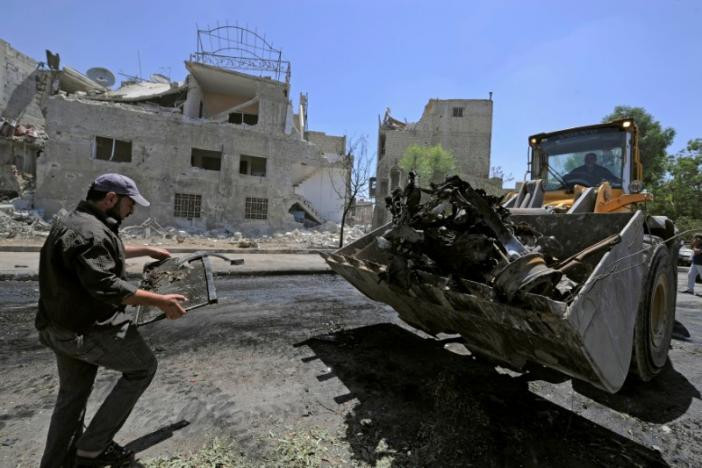 Người đàn ông đang dọn dẹp khu vực vừa xảy ra vụ đánh bom ở thủ đô Syria.