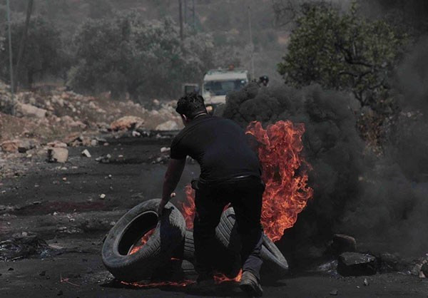 Người biểu tình Palestine đốt lốp xe trong cuộc đụng độ. Ảnh: FNA.