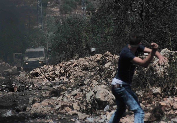Người biểu tình Palestine ném đá về phía binh sĩ Israel. Ảnh: FNA.