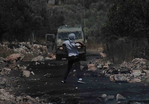 Một người Palestine ném đá về phía các binh sĩ Israel trong cuộc biểu tình chống lại việc mở rộng khu định cư Do Thái ở làng Kurf Qadoom gần thành phố Nablus. Ảnh: FNA.