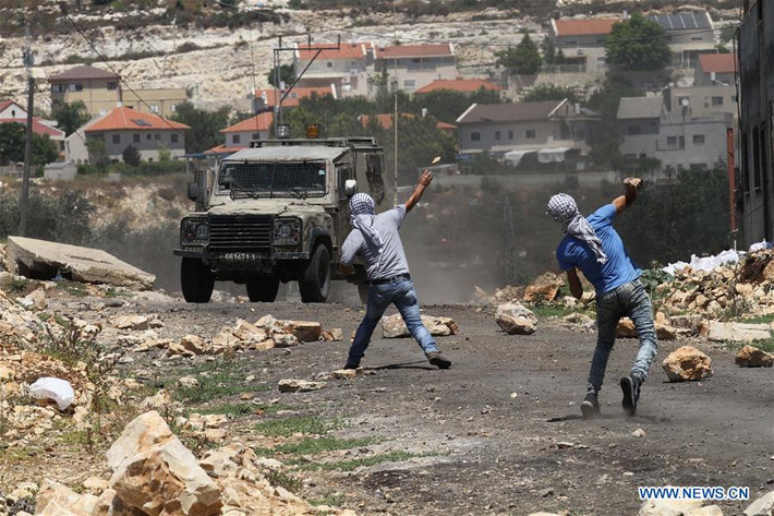 Hai thanh niên Palestine ném đá vào các binh sĩ Israel hôm 23/6. Ảnh: THX.