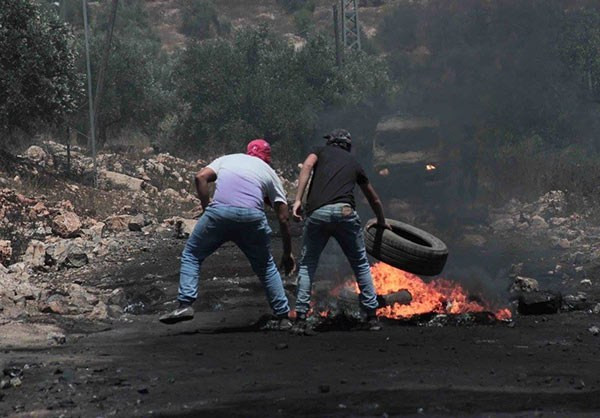Khói đen bốc lên sau khi người biểu tình Palestine đốt lốp xe trước mặt các binh sĩ Israel. Ảnh: FNA.