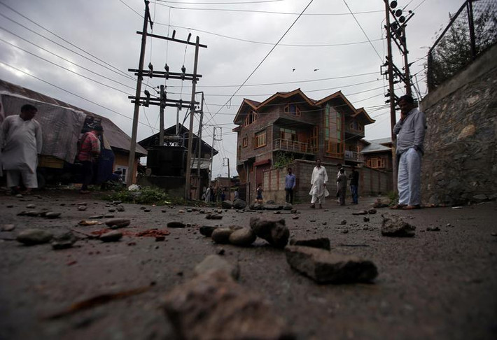 Người dân đi qua con đường ngổn ngang gạch đá ở Srinagar, thủ phủ vùng Kashmir, ngày 14/8.