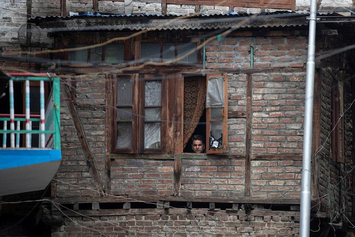 Người đàn ông Kashmir nhìn ra ngoài cửa sổ ở Srinagar hôm 14/8.