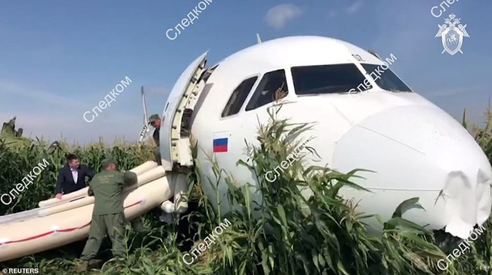 Hành khách ra khỏi máy bay bằng cầu thang phao, sau khi máy bay hạ cánh khấn cấp trên cánh đồng ngô. Ảnh: Reuters.
