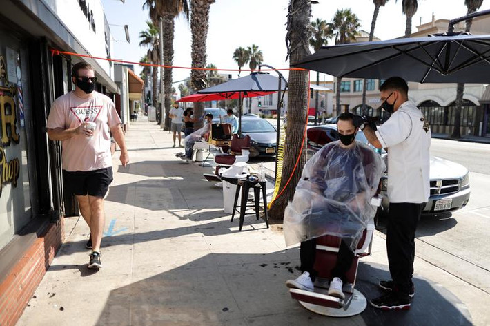 Keith Huerta, 30 tuổi, đeo khẩu trang khi cắt tóc cho Nick Parr, 25 tuổi, trên đường phố ở Santa Monica, California, Mỹ, ngày 2/9. Được biết, Mỹ hiện vẫn là vùng dịch lớn nhất thế giới.