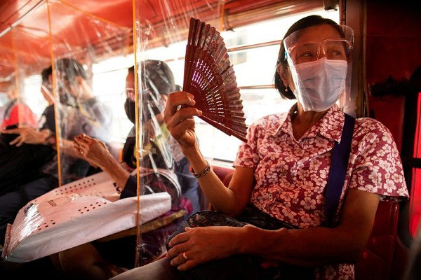 Hành khách đi phương tiện công cộng tại Quezon, Metro Manila, Philippines, bắt buộc phải đeo khẩu trang và đội mũ chống giọt bắn để ngăn ngừa lây nhiễm virus. Giữa các hành khách là tấm màn nhựa ngăn cách.