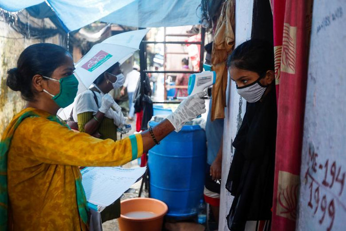 Một tình nguyện viên kiểm tra thân nhiệt người dân tại khu ổ chuột ở Mumbai, Ấn Độ, ngày 17/8.