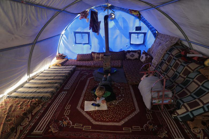 Bé trai Mahmoud Abdel Hadi, 8 tuổi, làm bài tập về nhà tại khu trại Atmeh, Syria, ngày 30/3. Trường học của Hadi đã bị đóng cửa trong thời gian này.