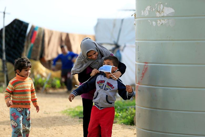 Người phụ nữ Syria đeo khẩu trang cho con trai phòng lây nhiễm virus tại khu trại ở al-Wazzani, phía nam Lebanon, ngày 14/3.