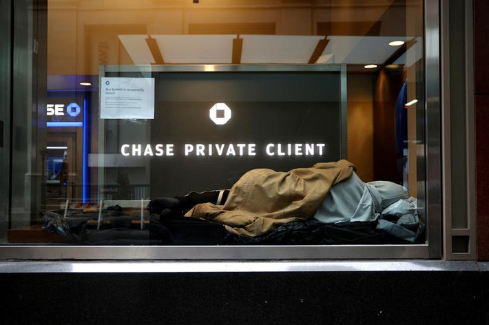Người vô gia cư nằm ngủ trong một chi nhánh ngân hàng Chase bị đóng cửa trên phố Wall ở Manhattan, New York.