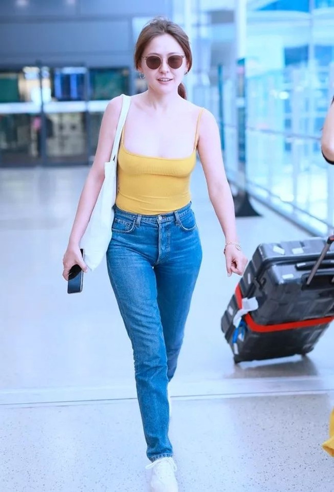 Nữ diễn viên Nhiệt Y Trát xuất hiện ở sân bay với trang phục gồm áo hai dây cổ sâu kết hợp với quần jean.