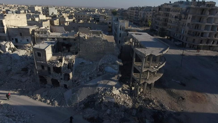 Người dân đi qua những tòa nhà đổ nát tại khu vực do phe nổi dậy kiểm soát tại Aleppo hôm 27/9.
