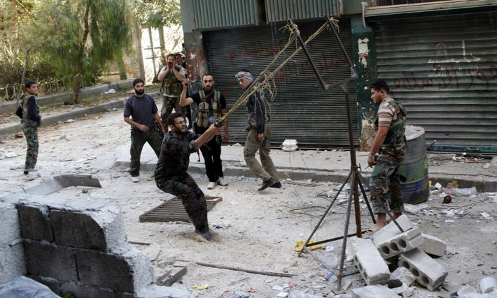 Thêm một loai vũ khí tự chế được FSA sử dụng trong cuộc giao tranh với quân đội Syria. Ảnh: Chiến binh FSA dùng súng cao su để phóng một quả bom tự chế về phía binh sĩ quân đội Syria ở thành phố Aleppo hồi tháng 10/2012.
