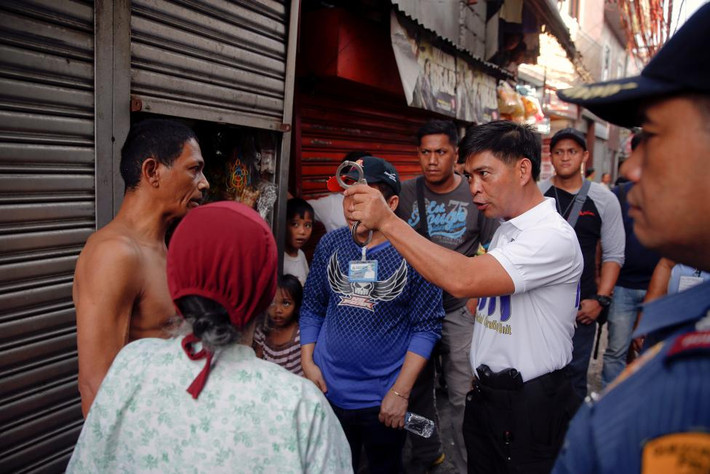 Một cảnh sát Philippines giơ còng tay trước mặt một người dân trong chiến dịch chống ma túy ở thành phố Quezon hôm 12/10.
