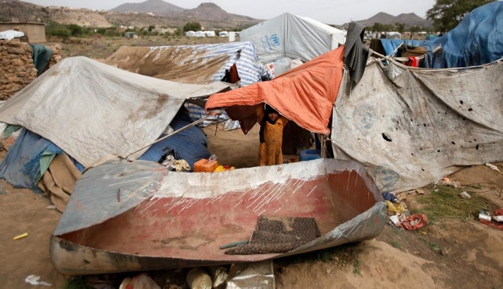 Một bé gái đứng trong khu trại lụp xụp dành cho người dân sơ tán khỏi chiến tranh ở Yemen.