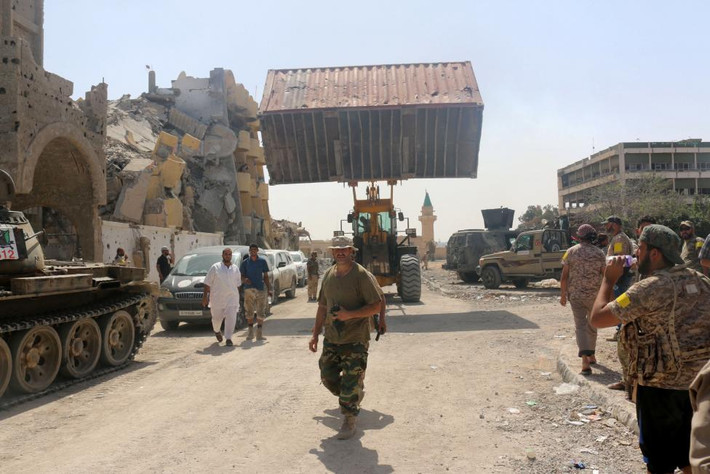 Các tay súng lực lượng Libya tập trung bên ngoài những tòa nhà bị phá hủy mà họ vừa giành lại được quyền kiểm soát từ tay tổ chức khủng bố IS ở khu Number Three ngày 3/10.
