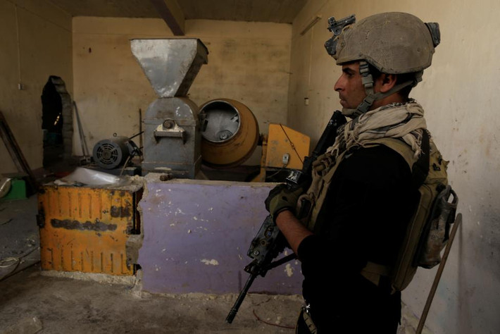 Một binh sĩ đặc nhiệm Iraq đứng trong một nhà máy từng được phiến quân IS sử dụng để chế tạo bom ở Bazwaya.