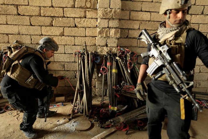 Một binh sĩ Iraq kiểm tra thiết bị nổ trong một nhà máy từng được nhóm IS sử dụng để chế tạo bom ở Bazwaya hôm 27/10.