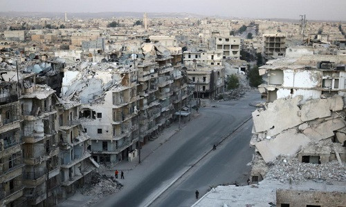 Người dân đi qua những tòa nhà cao tầng bị phá hủy ở khu Tariq al-Bab hôm 5/10.
