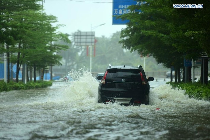 Một chiếc ô tô cố vượt qua đoạn đường ngập lụt ở thành phố Quỳnh Hải. Ảnh: News.cn.