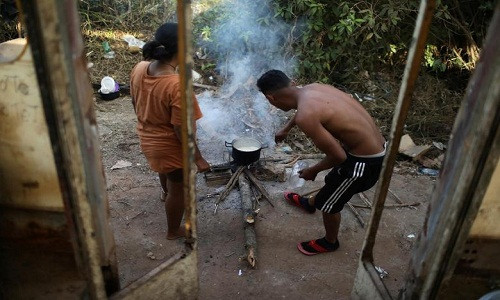 Hildemaro Ortiz và Ixora Sanguino nấu ăn gần xe buýt. "Giá mà chiếc xe buýt này còn hoạt động, chúng tôi sẽ di chuyển tới Manaus ngay bây giờ", Ortiz nói.