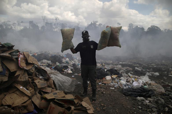 Một người đàn ông Venezuela cầm những chiếc gối tại bãi rác ở Pacaraima.