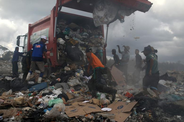 Hơn chục người dân Venezuela bới rác tìm đồ sau khi chiếc xe tải đổ rác xuống khu vực này.