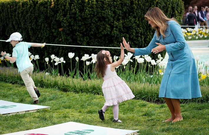 Đệ nhất phu nhân Mỹ Melania Trump đập tay với một em nhỏ tại bãi cỏ ở Nhà Trắng ngày 22/4.