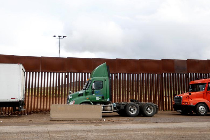 Những chiếc xe tải xếp hàng dài cạnh bức tường biên giới Mỹ-Mexico.