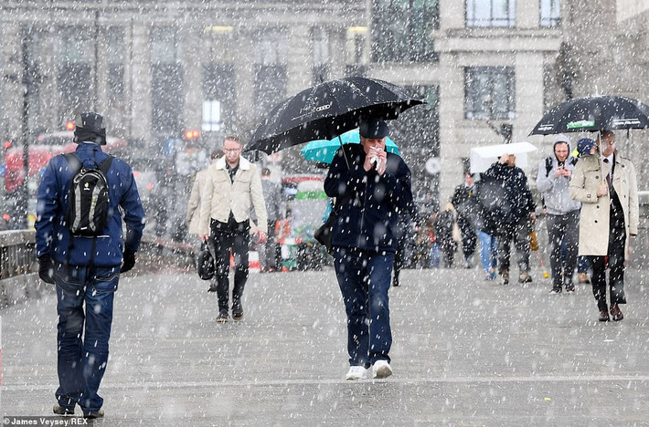 Nhiều người phải che ô khi đi dưới trời mưa tuyết trên cầu London.
