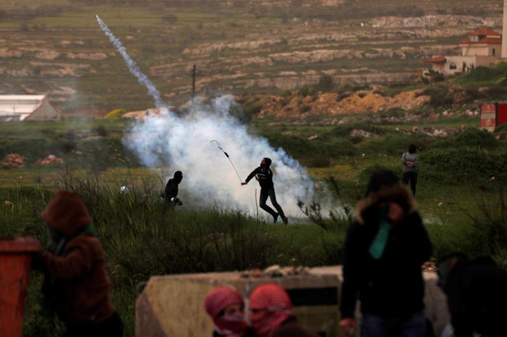 Một người Palestine ném trả lựu đạn hơi cay về phía lực lượng an ninh Israel trong cuộc xung đột gần khu định cư Do Thái Beit El ngày 30/3.