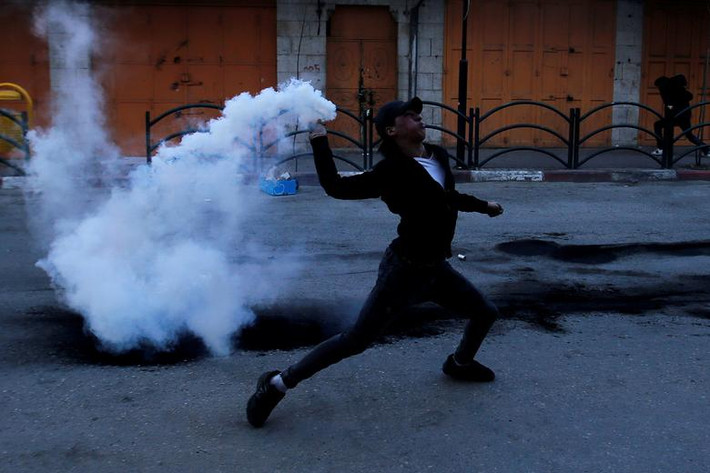 Một người biểu tình Palestine ném trả lựu đạn hơi cay về phía lực lượng an ninh Israel ở Hebron, Bờ Tây.