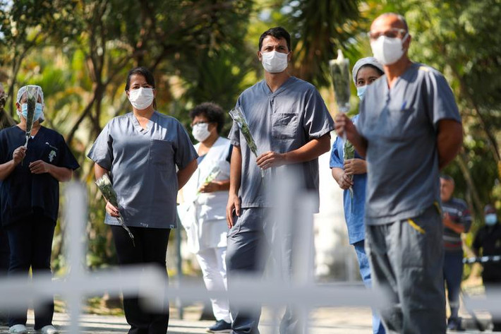 Nhân viên y tế cầm hoa tưởng nhớ đồng nghiệp Maria dos Santos, y tá tử vong vì COVID-19, bên ngoài một bệnh viện ở Sao Paulo, Brazil, ngày 23/4.