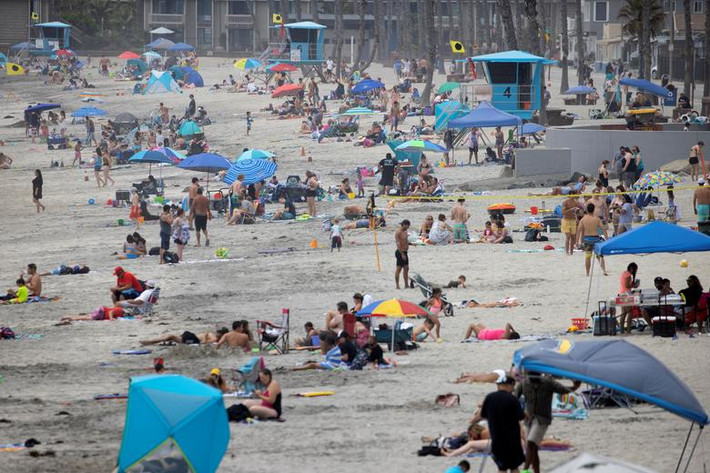 Thống đốc bang California Gavin Newsom yêu cầu người dân đeo khẩu trang, giữ khoảng cách an toàn và thường xuyên rửa tay để đề phòng lây nhiễm virus. Ảnh: Nhiều người tập trung trên bãi biển ở Oceanside, California, hôm 22/6.